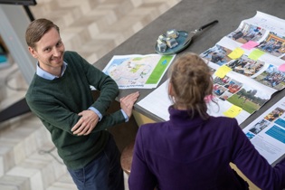 Rutger staat aan een tafel waar gebrainstormd wordt met post-its